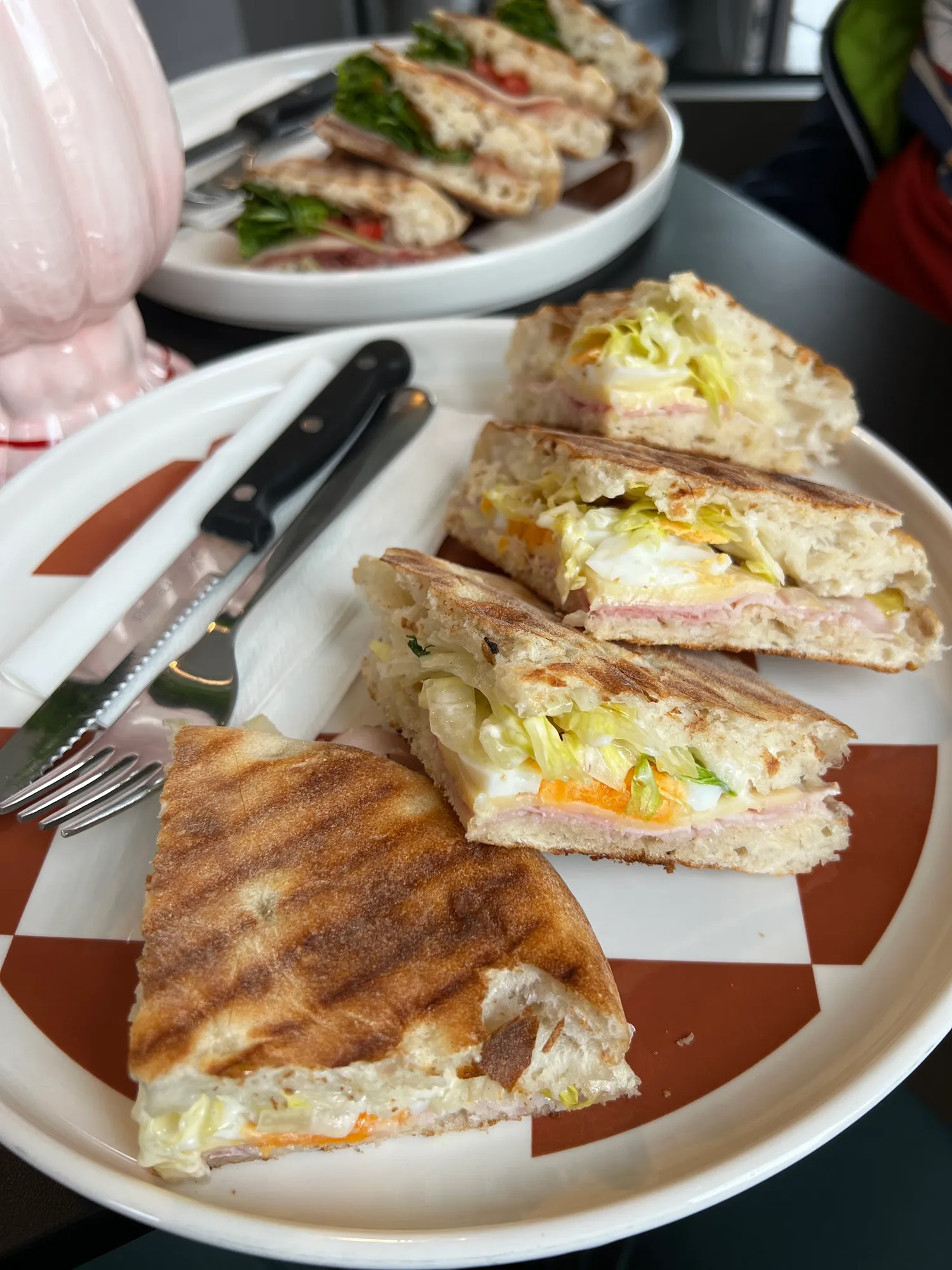 Getoastete Focaccia-Sandwiches mit Ei, Schinken und Salat auf einem karierten Teller